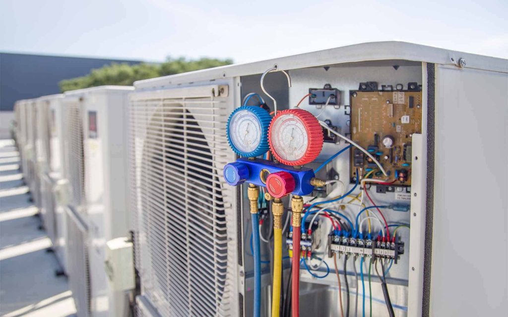 Air conditioning HVAC service technician using gauges to check refrigerant and add refrigerant.