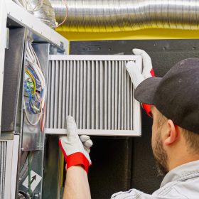 HVAC service technician changing dirty air filter in the central ventilation system. Change filter in rotary heat exchanger recuperator. Air duct ventilation system maintenance for clean air.